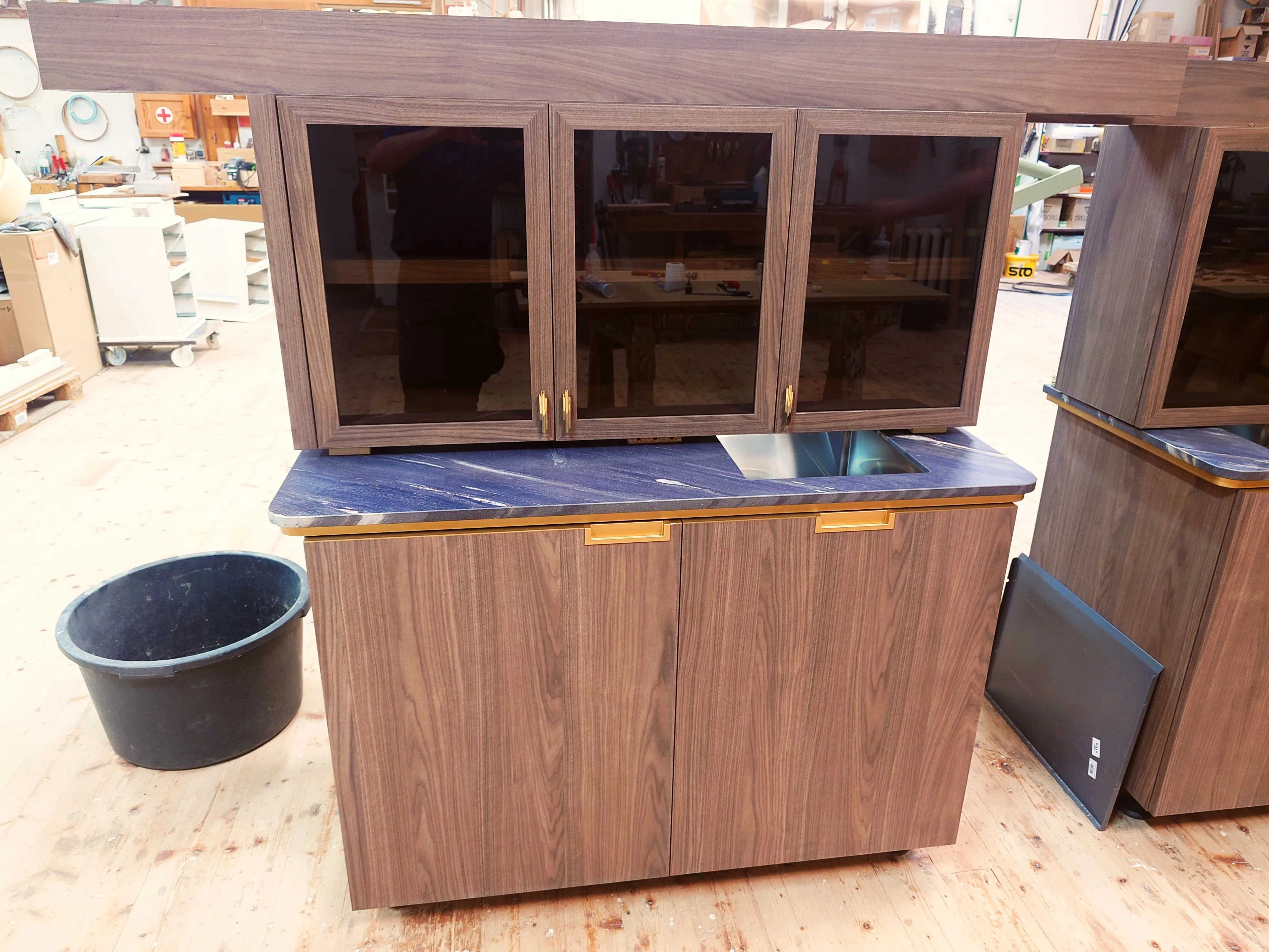 Hängeschrank mit Glastüren über Unterschrank mit Spülenausschnitt und Natursteinplatte